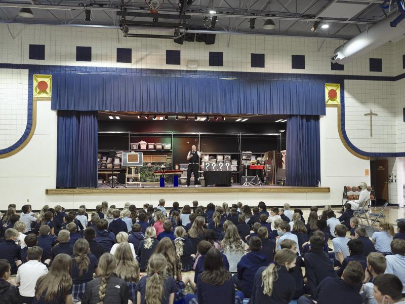 Scott Henderson on stage performing a full production magic show at a Kansas City school